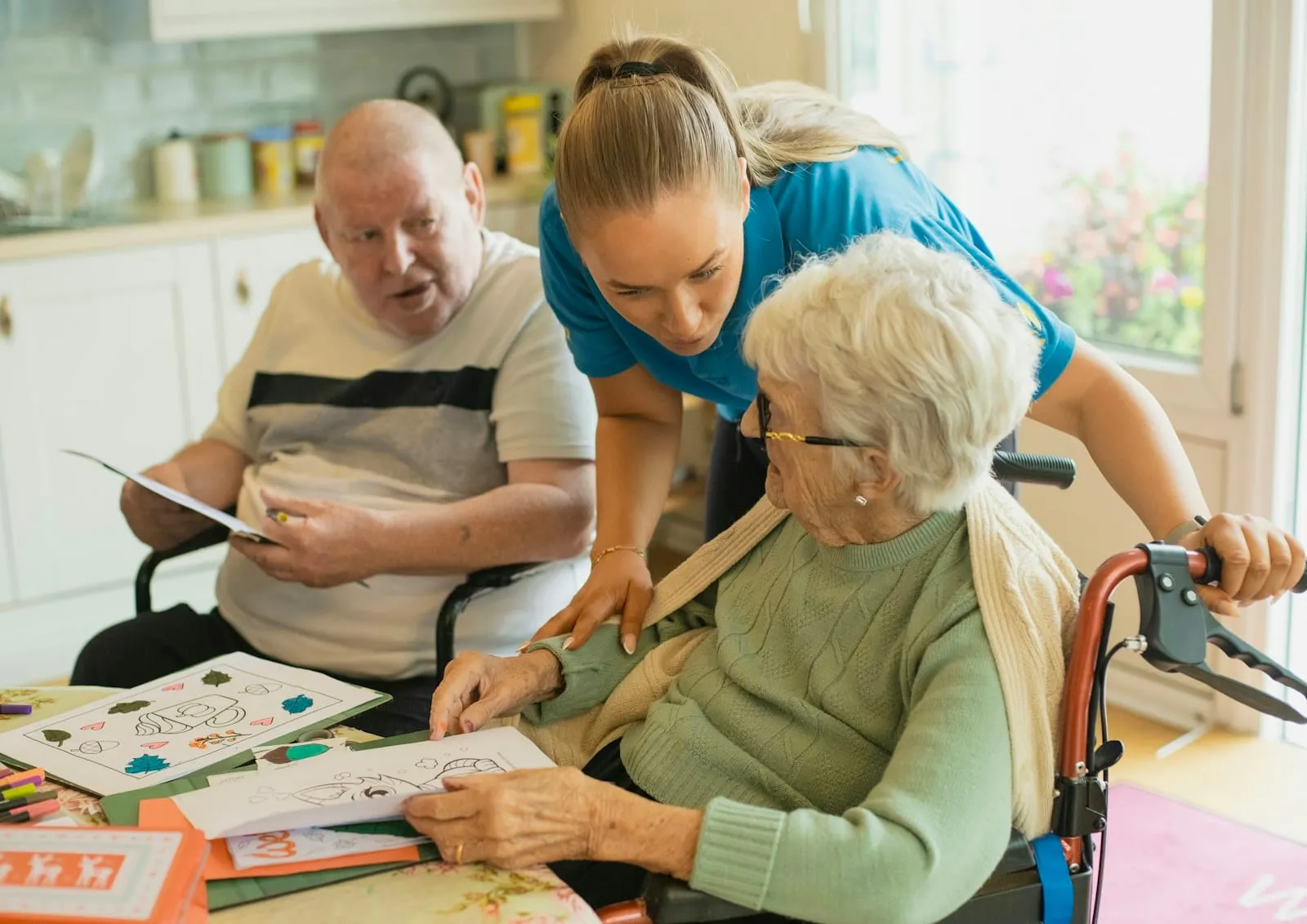 A care worker sitting with two residents at a table