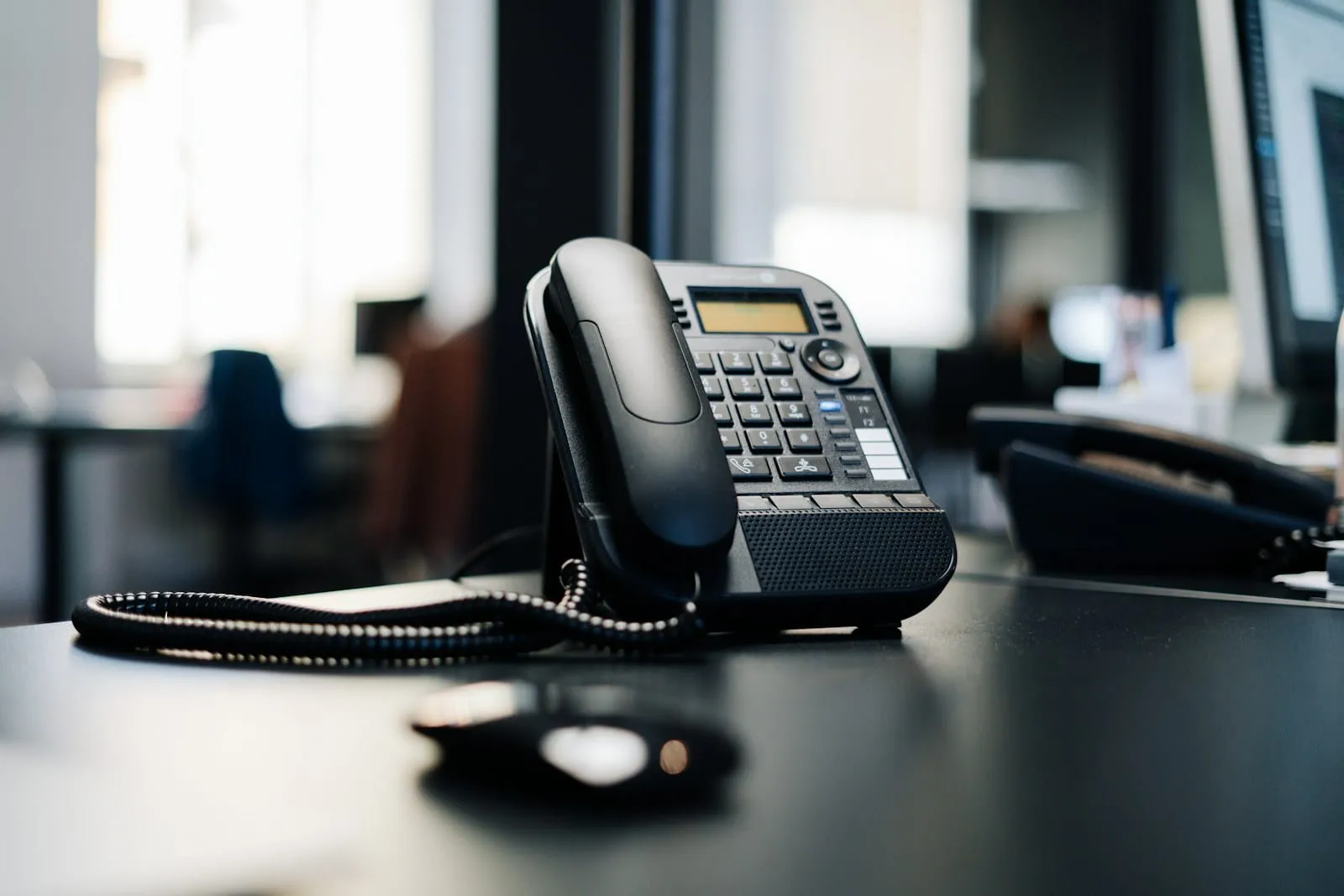 An IP desk phone on a dark wooden desk